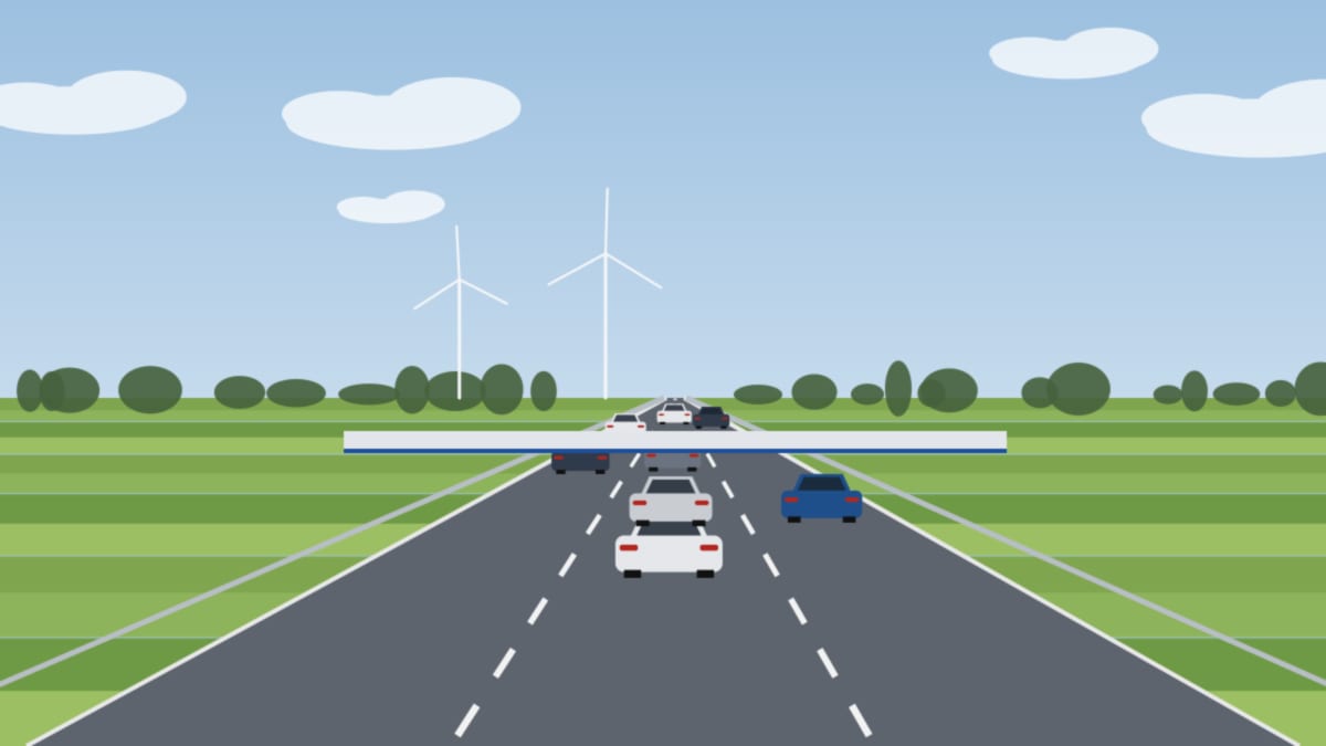 Autobahn an der Grenze mit dichtem Verkehr vor einer flachen Kontrollüberdachung, grüne Felder ringsum
