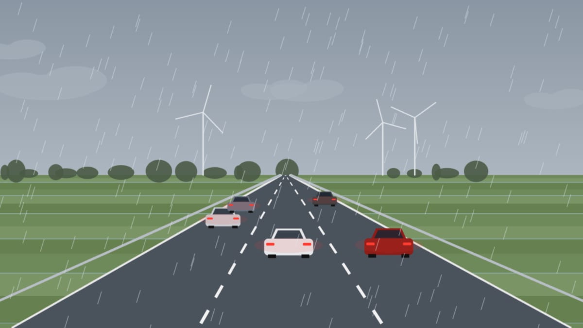 Nasse Autobahn im Regen mit roten Rücklichtern vor grauen Wolken über flachem Land