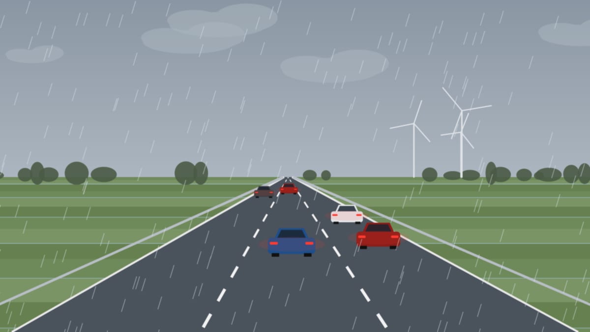 Nasse Autobahn bei Sturm und Regen, graue Wolken und Windräder über flachem Land