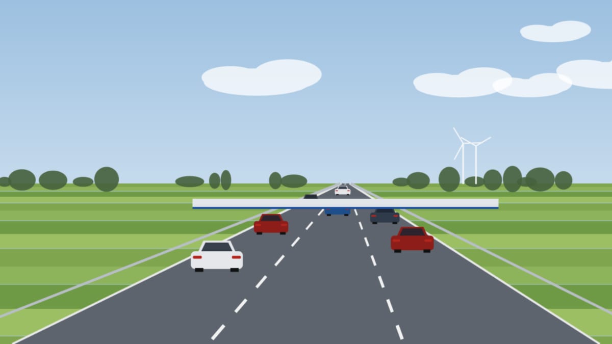 Autobahn nahe der Grenze mit Fahrzeugen in mehreren Spuren, flache Felder und Windräder im Hintergrund