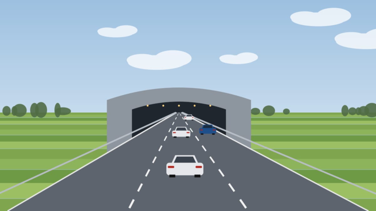 Autobahn führt in ein beleuchtetes Tunnelportal, ringsum grüne flache Landschaft