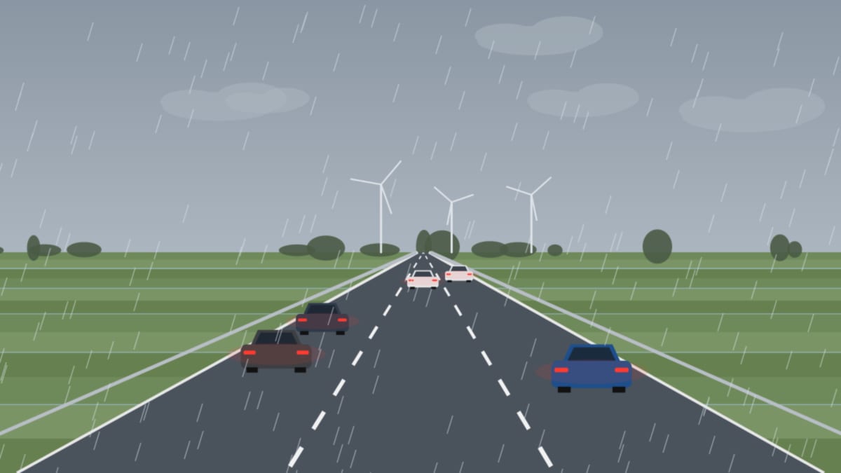 Nasse Autobahn im Regen mit roten Rücklichtern und Windrädern im grauen Hintergrund